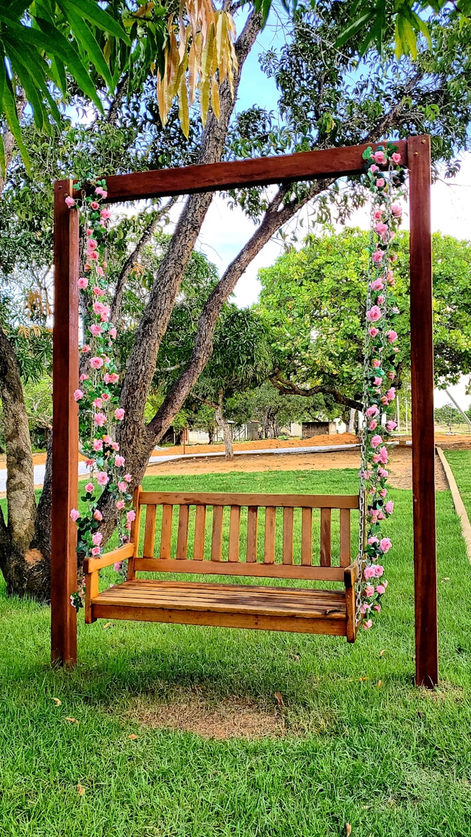 brown wooden bench under green and pink leaf tree