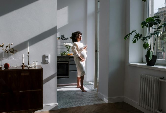 Expectant mother in a cozy sunlit kitchen, embracing new life with style and grace.